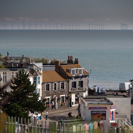 View of Broadstairs with houses and green park in foreground, sea in background and offshore wind turbines on horizon