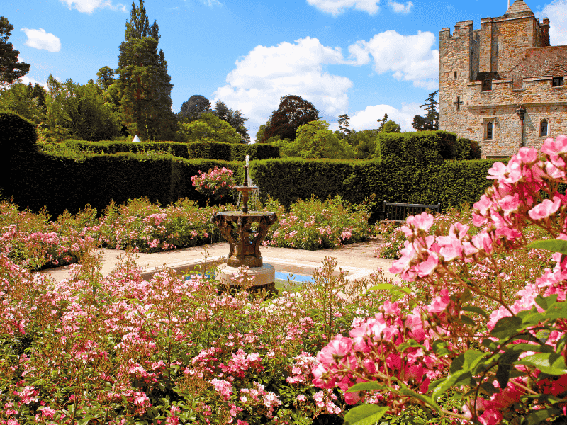 The Rose Garden at Hever Castle in full bloom, with a central fountain and castle view — featured on the Anderson Tours Leeds and Hever Castle Day Tour from London.