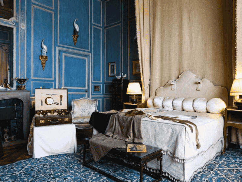 State Bedroom at Leeds Castle featuring blue panelled walls, a grand canopy bed, and period furnishings — part of the Anderson Tours Leeds and Hever Castle Day Tour from London.